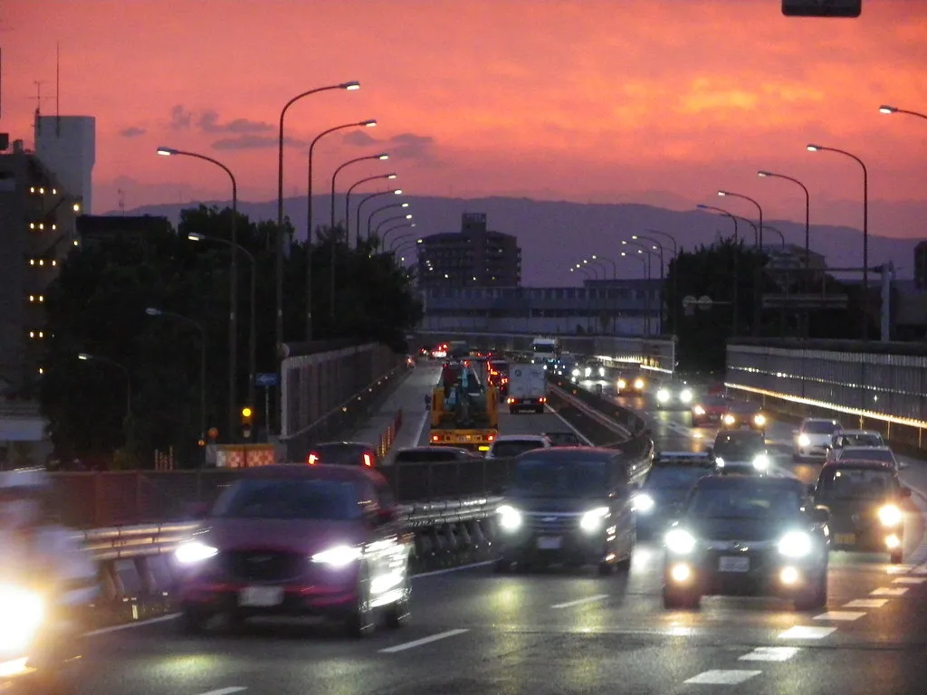 Evening traffic with headlights on a bridge in Nagoya under a red sky
