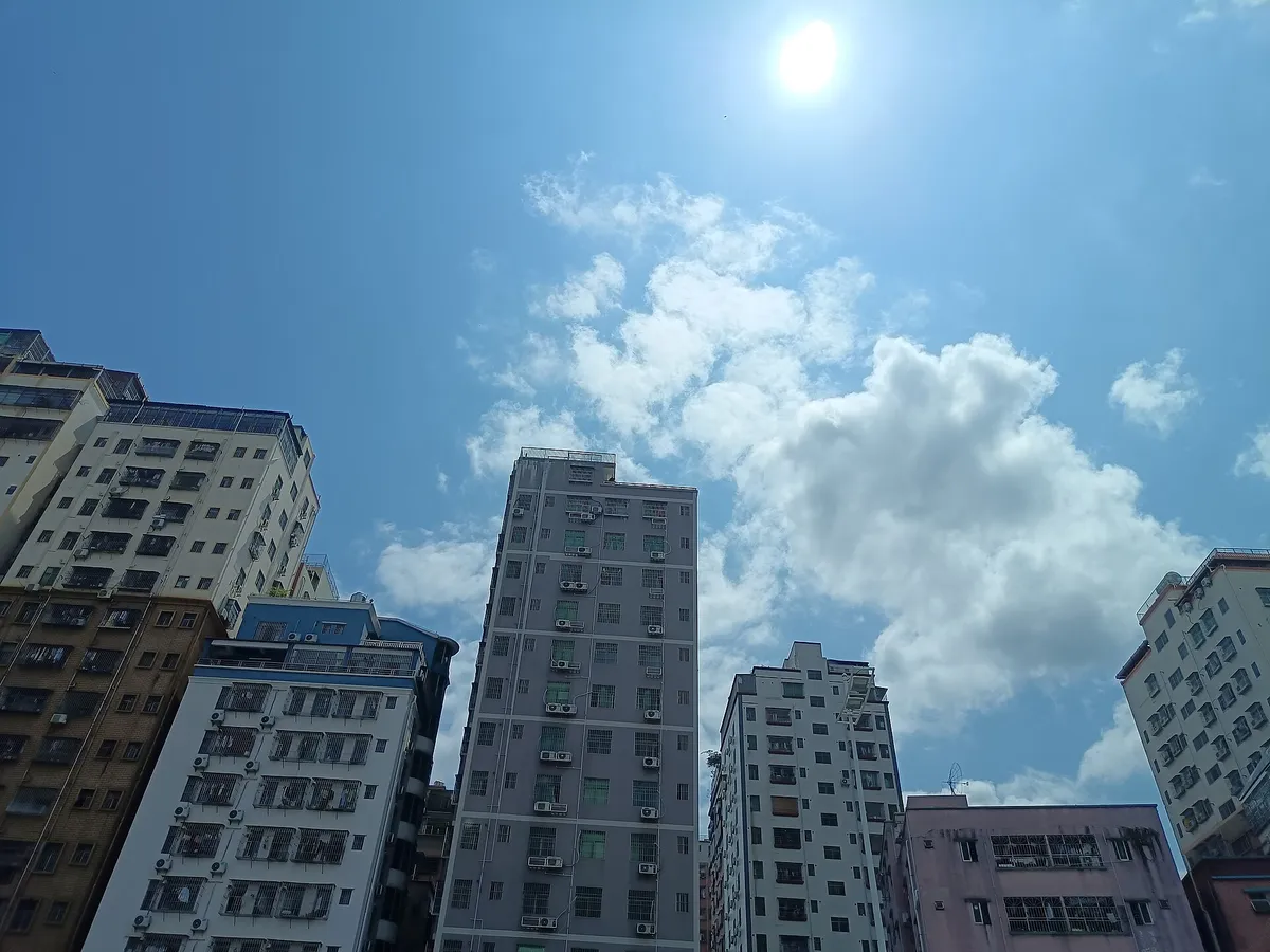 Tall residential towers in Shenzhen seen from street level against a blue sky