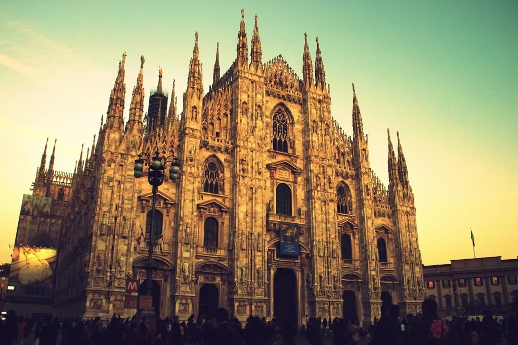 The Gothic facade and spires of Milan Cathedral glowing in warm evening light