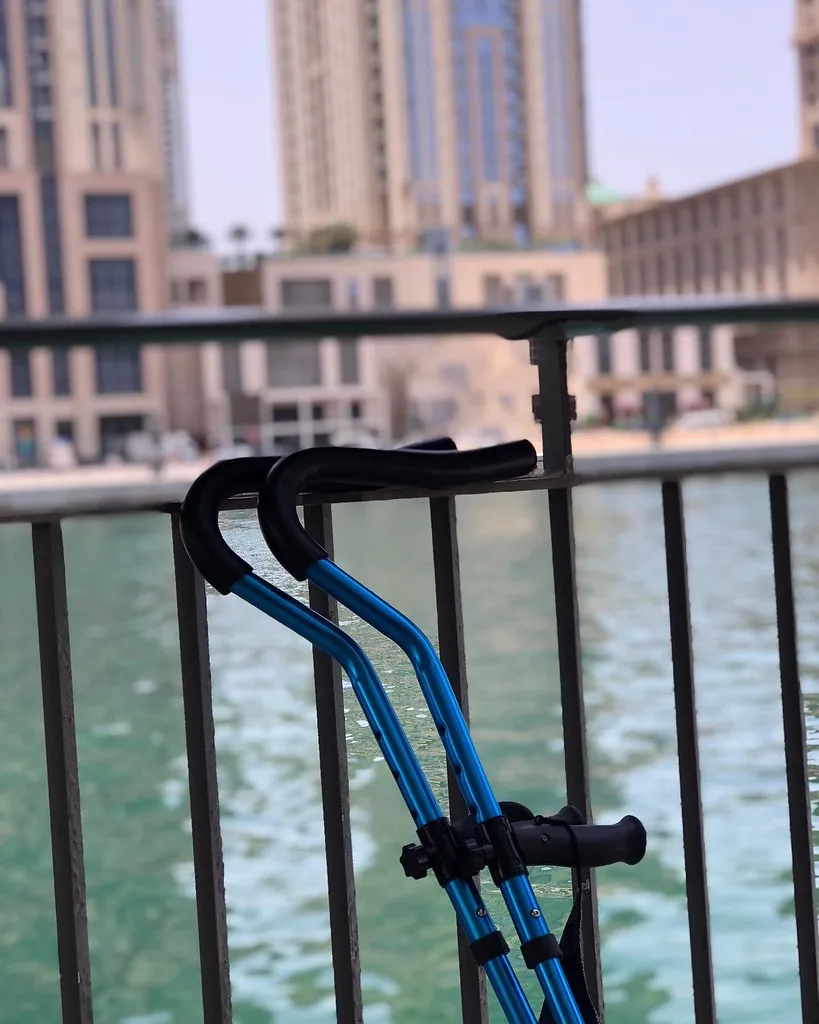 A pair of blue forearm crutches leaning against a black metal railing