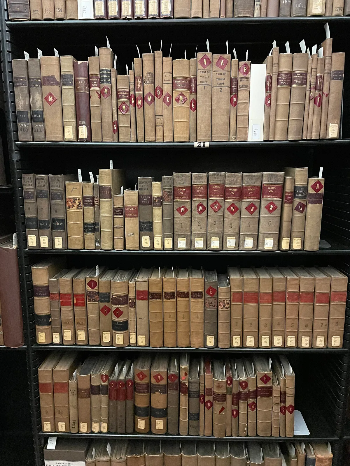 Rows of old leather-bound law volumes with red and gold spines on library shelves