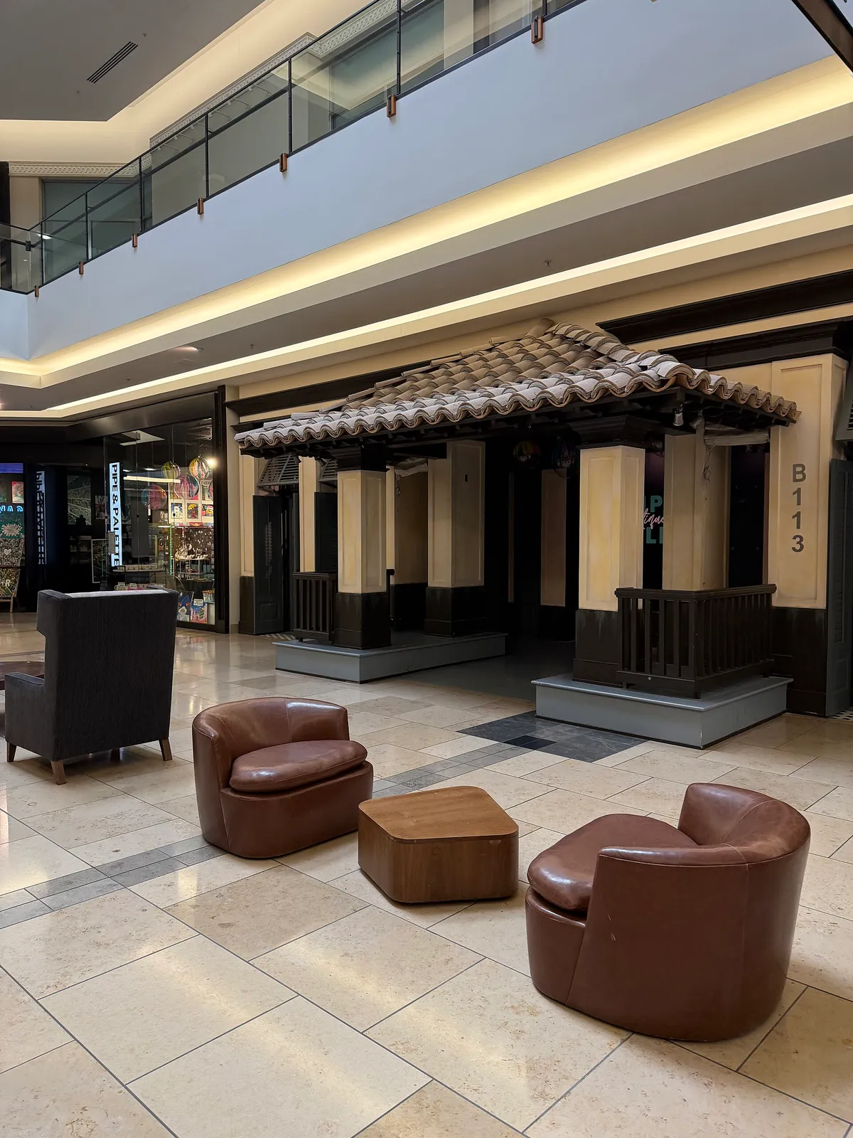 A vacant retail space with a tiled awning and armchairs in a Dallas-area shopping mall