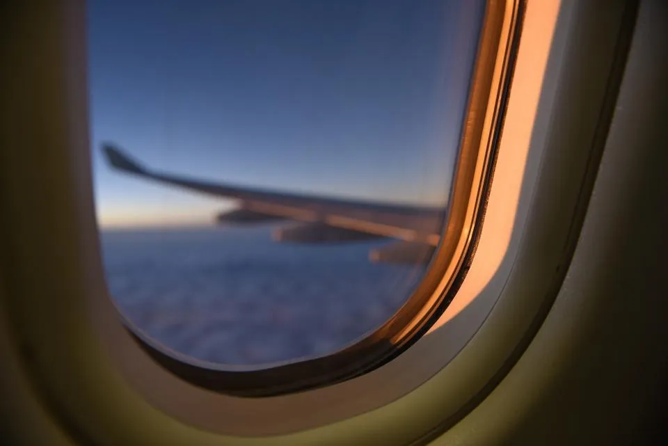 View of a plane wing at sunset through an airplane window