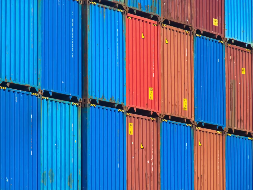 A wall of stacked blue, red and orange shipping containers