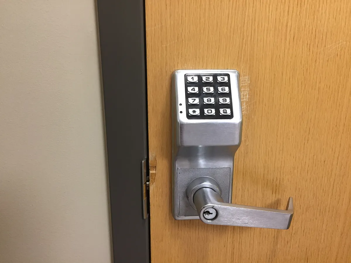 A push-button keypad lock with a lever handle on a wooden door