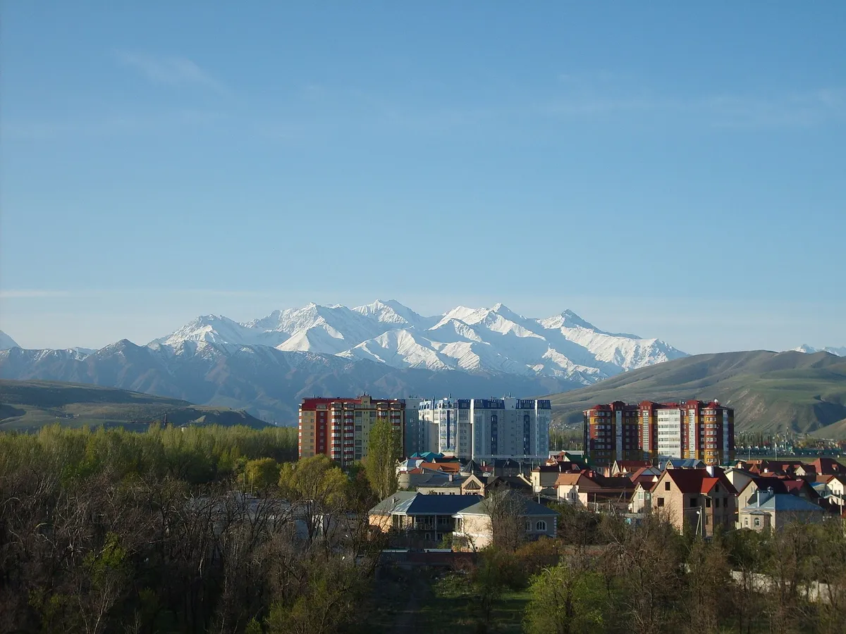 Apartment blocks and houses in Bishkek with snow-capped mountains rising behind the city