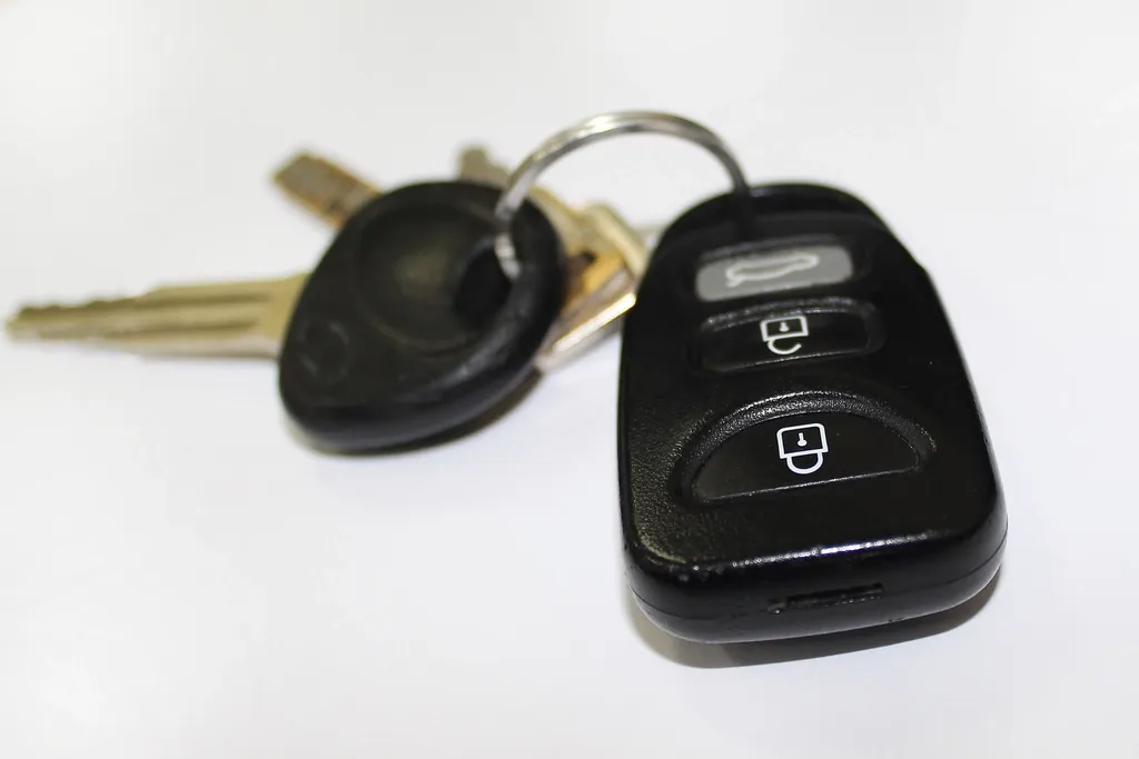 A car key with a remote fob and a second key on a ring, on a white surface
