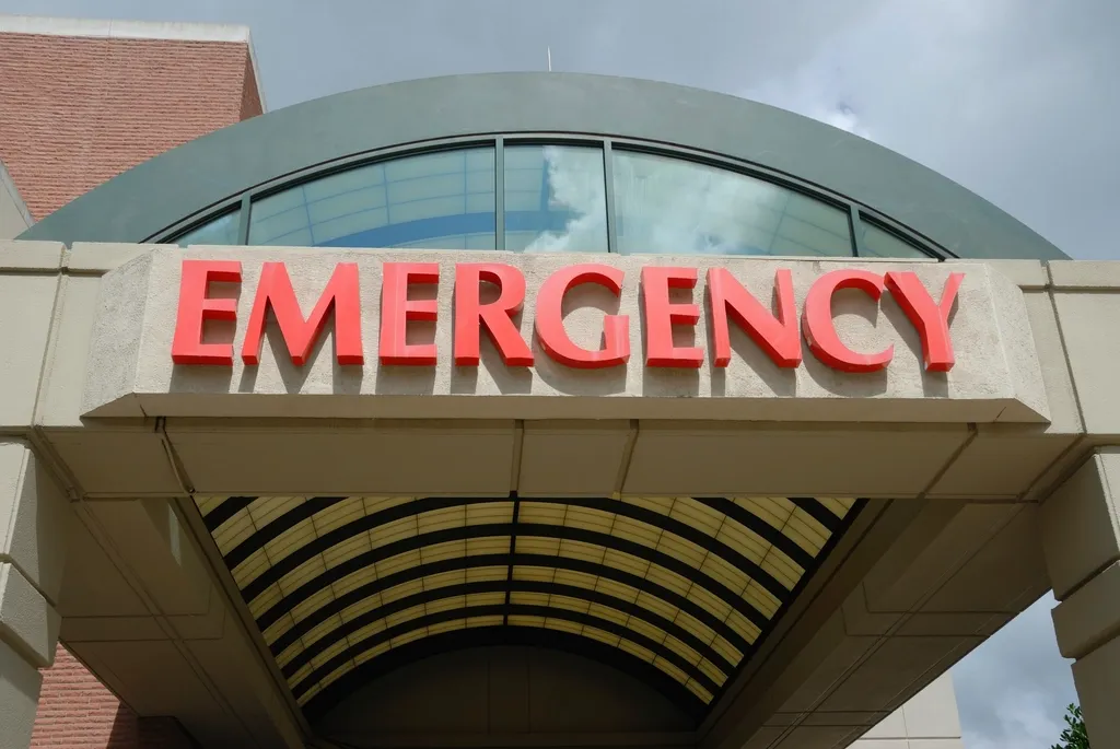 Red EMERGENCY letters on a curved canopy over a hospital entrance