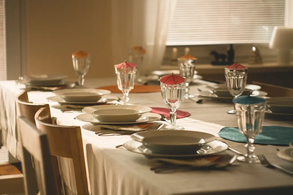 A long restaurant table set with white cloths, plates and stemmed glasses