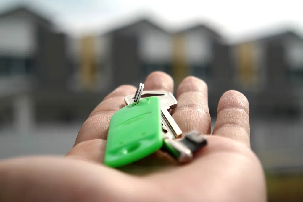 An open hand holding a set of house keys on a green key tag