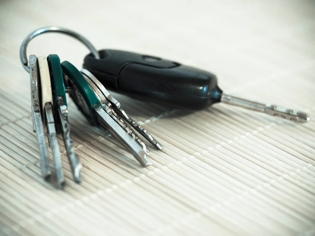 A ring of car keys with a black remote key lying on a ribbed light surface