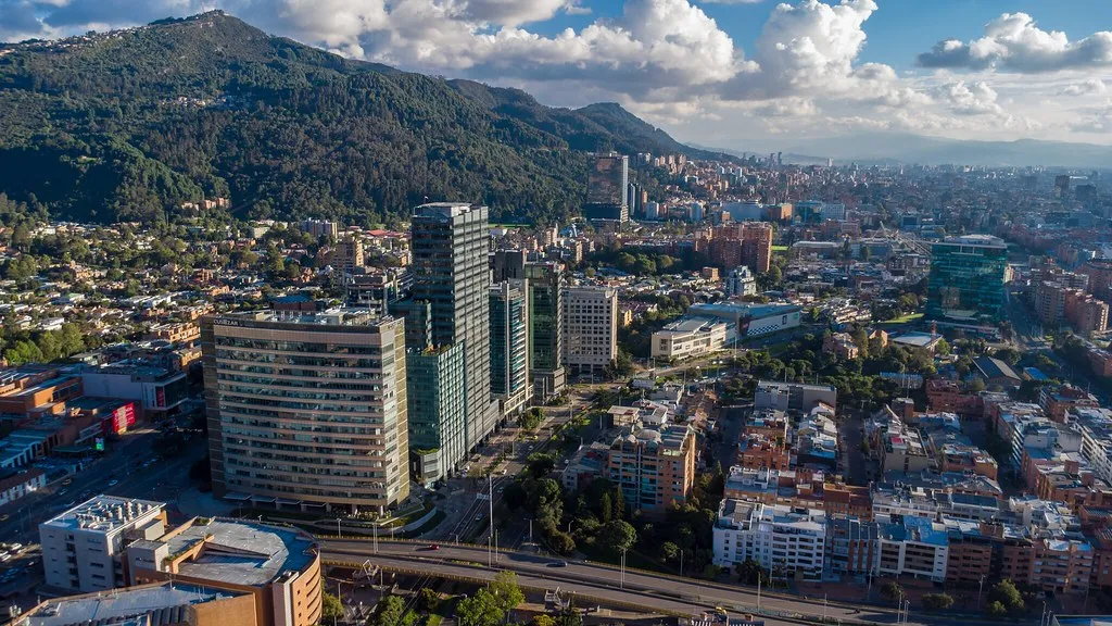Office towers and apartment blocks in Bogotá with green mountains behind them