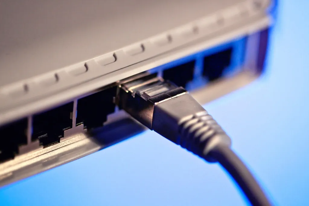 Close-up of a gray network cable plugged into a port on a white device