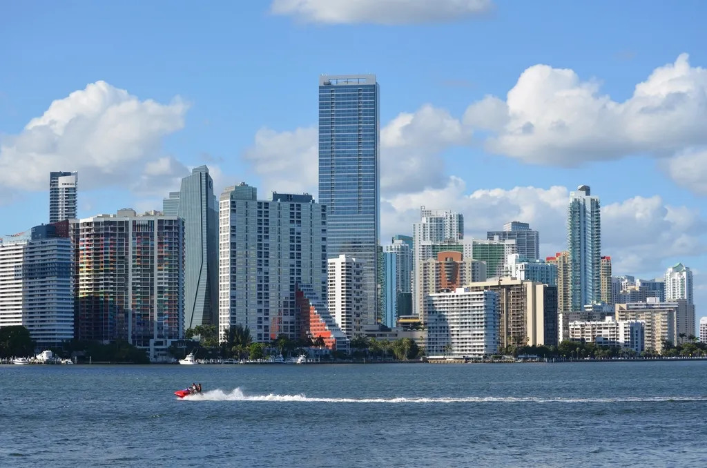 The Brickell skyline in Miami seen across Biscayne Bay under a blue sky with clouds