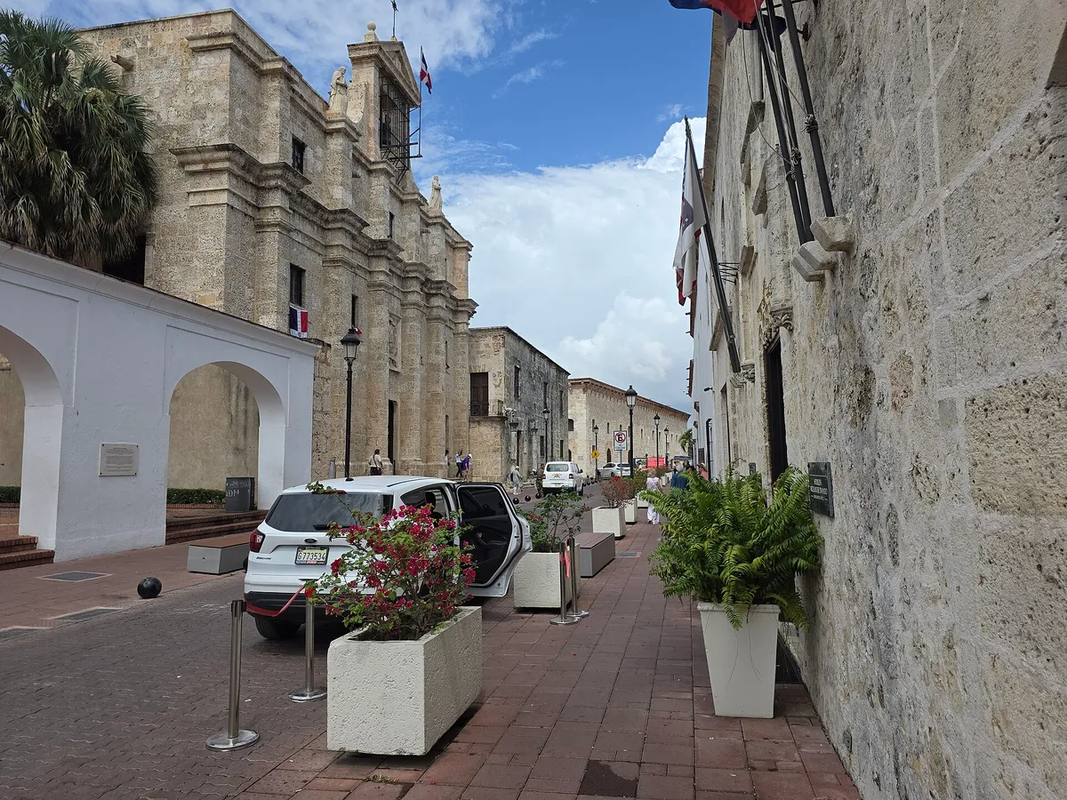 A narrow street of old stone buildings with white arches in Santo Domingo's colonial zone