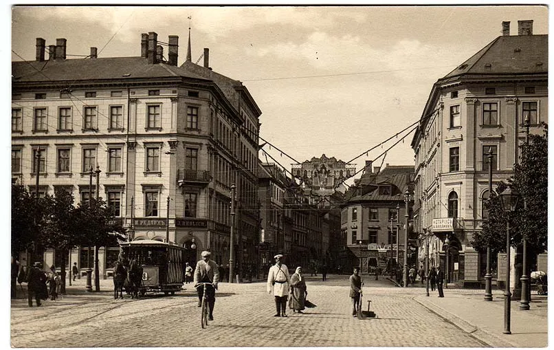 Old sepia photograph of a street in Riga's old town with tall stone buildings and a tram