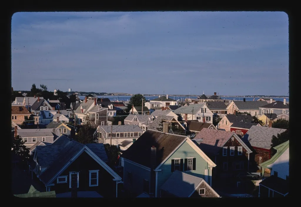 Weathered shingled rooftops of a dense New England town seen from above