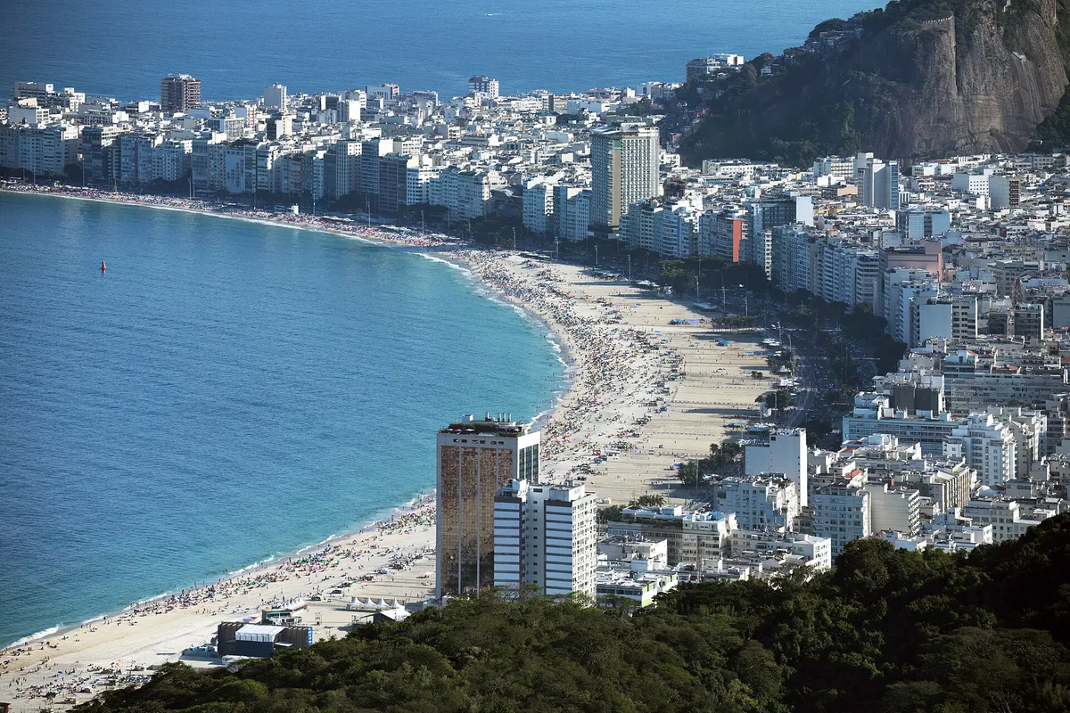 The long curved beach of Copacabana lined with apartment buildings seen from a hillside